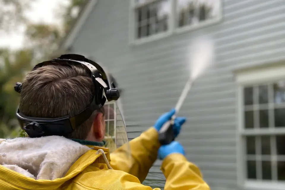 Operator pressure washing the siding of a family home