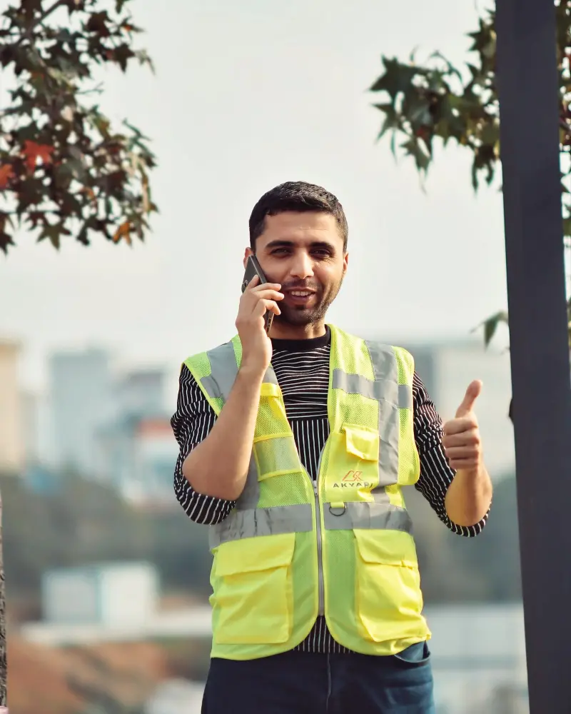 Tradesman in hi-vis taking a customer call and giving a thumbs up